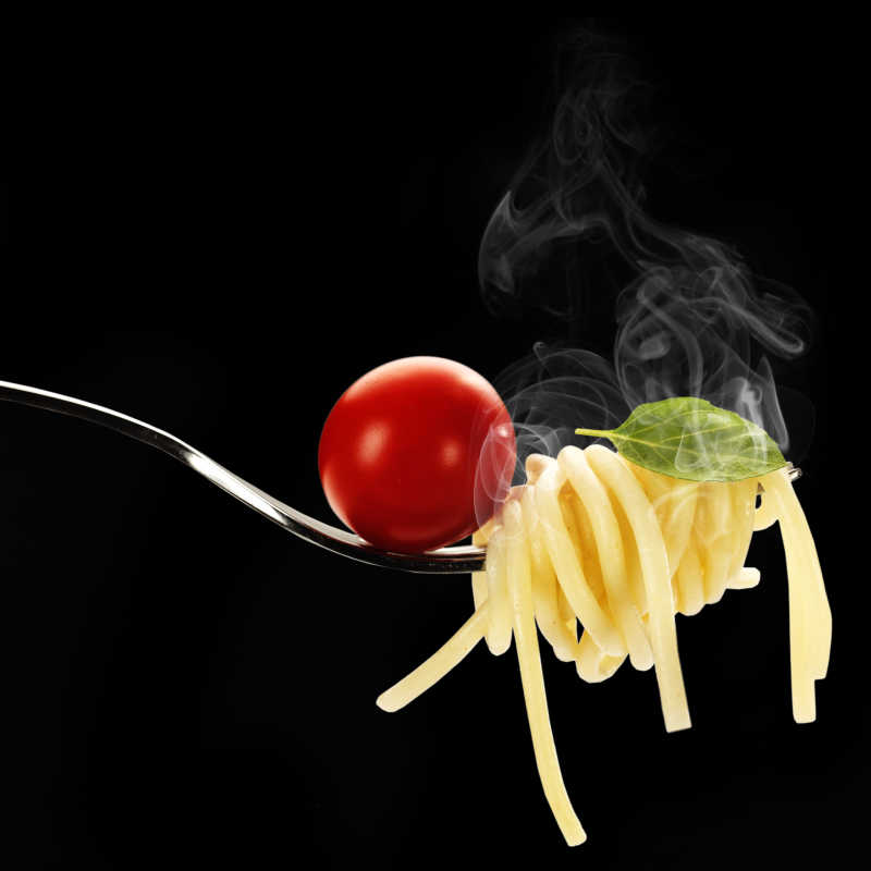 黑色背景前的番茄和意大利面