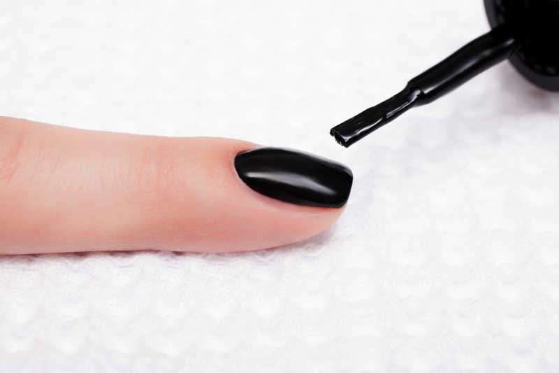 女人正在涂着黑色指甲油
