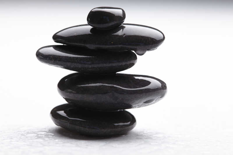 白色背景下滴着水的黑色鹅卵石