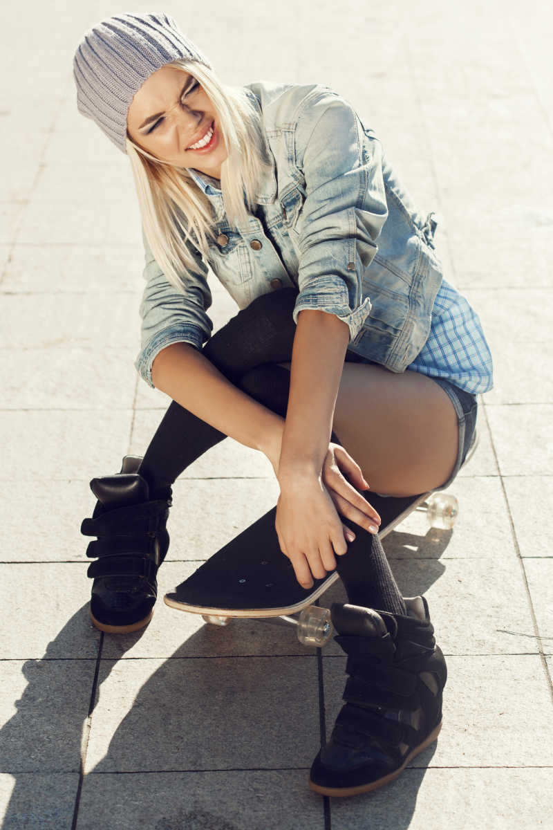坐在滑板上的年轻女孩