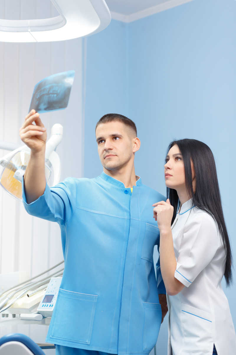 牙科医生和女性助理在牙科诊所看X光照