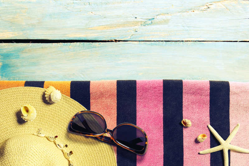 放在毛巾上的太阳镜遮阳帽