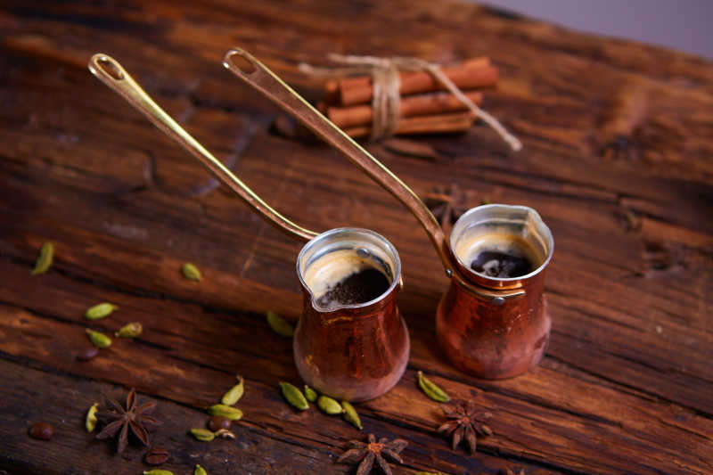 两杯装在金属长柄容器中的咖啡