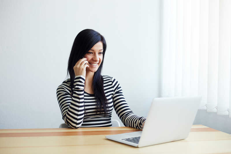 坐在办公桌前开心接电话的女人