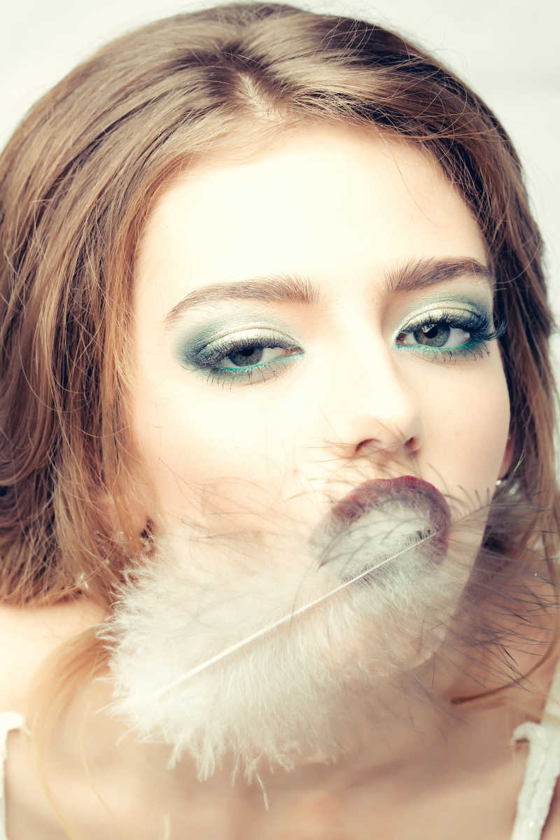 漂亮的女人拿羽毛挡着嘴