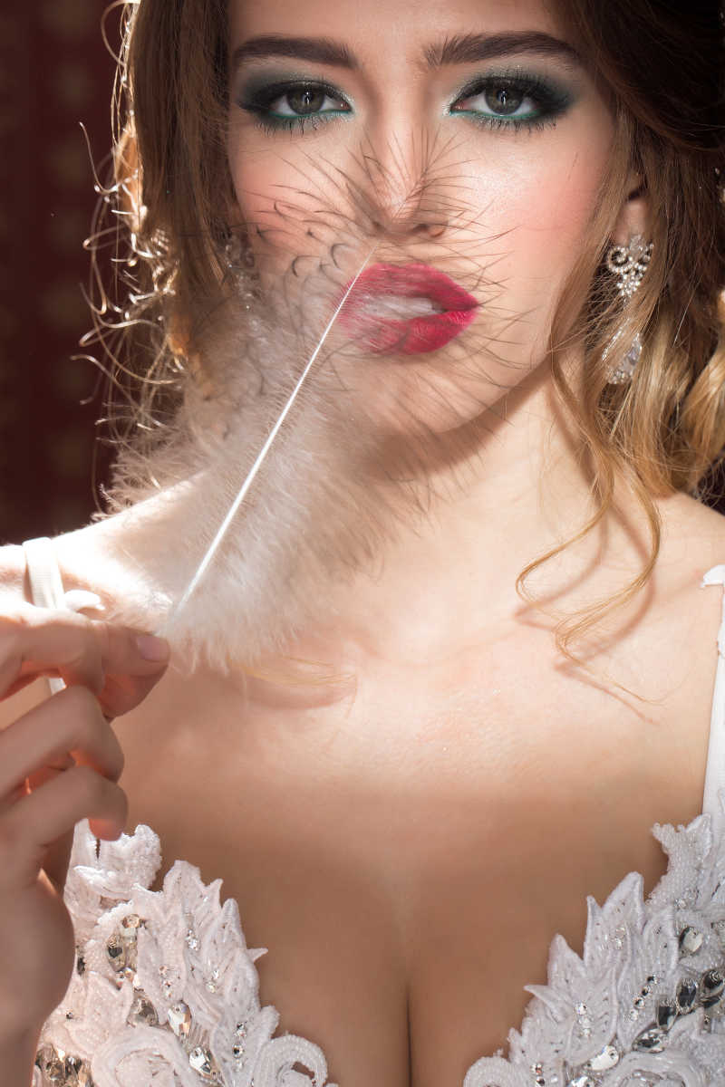 性感红唇美女拿着羽毛的特写