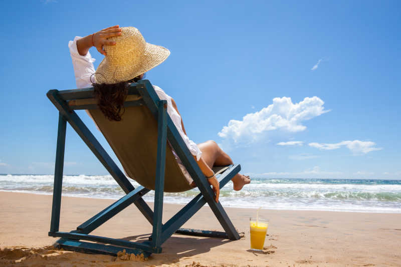 海边躺椅上的带着草帽的女人