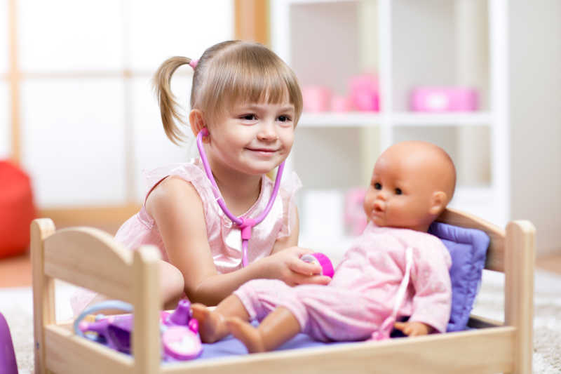 可爱的孩子给玩具娃娃看病