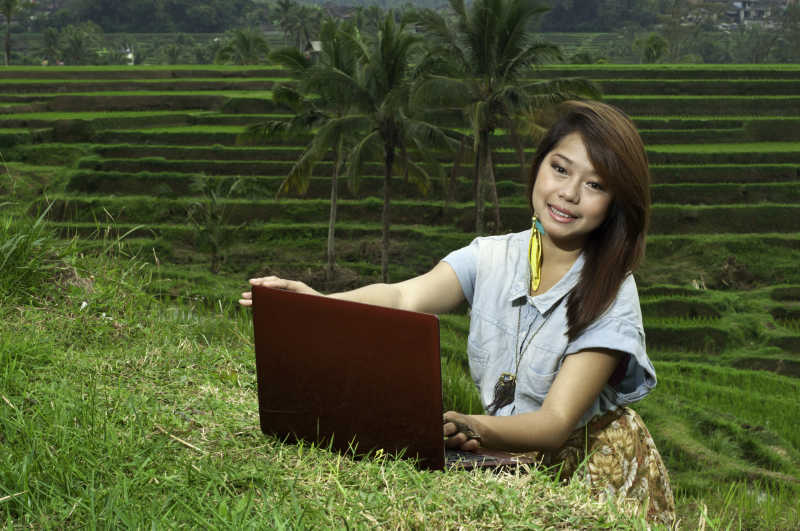 微笑的使用笔记本电脑的美女