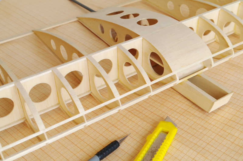 浅黄色桌面上的未完成的木制飞机模型