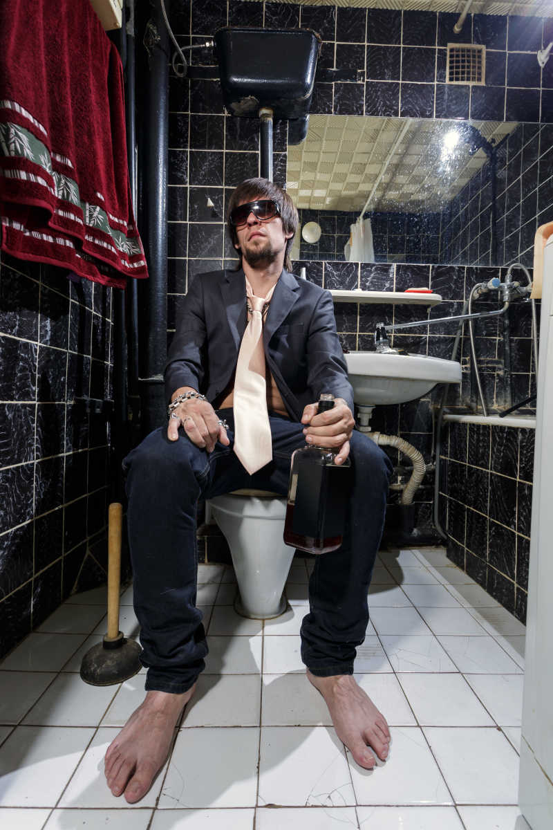 光着脚丫坐在马桶上喝酒的男人