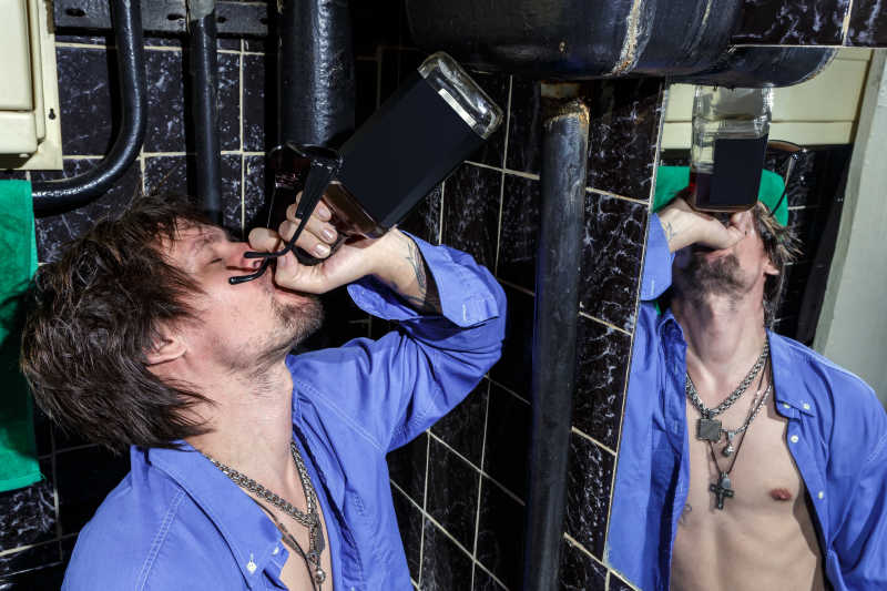 卫生间里对这镜子喝酒的男人