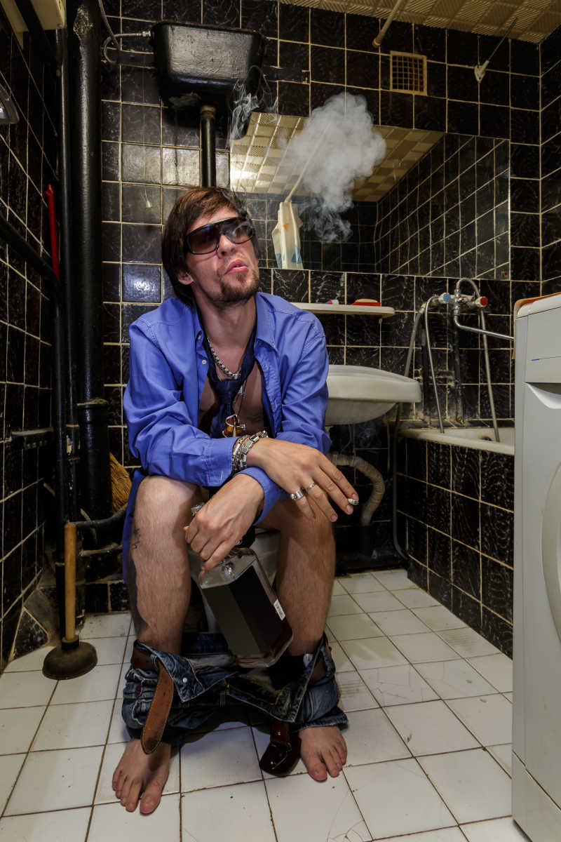 坐在马桶上吸烟的醉醺醺的男人