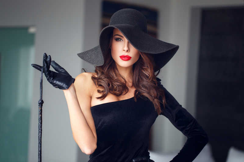 戴帽子的性感女人拿着鞭子