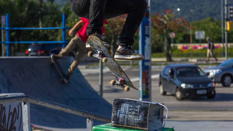 城市公园里玩滑板飞起下落的人