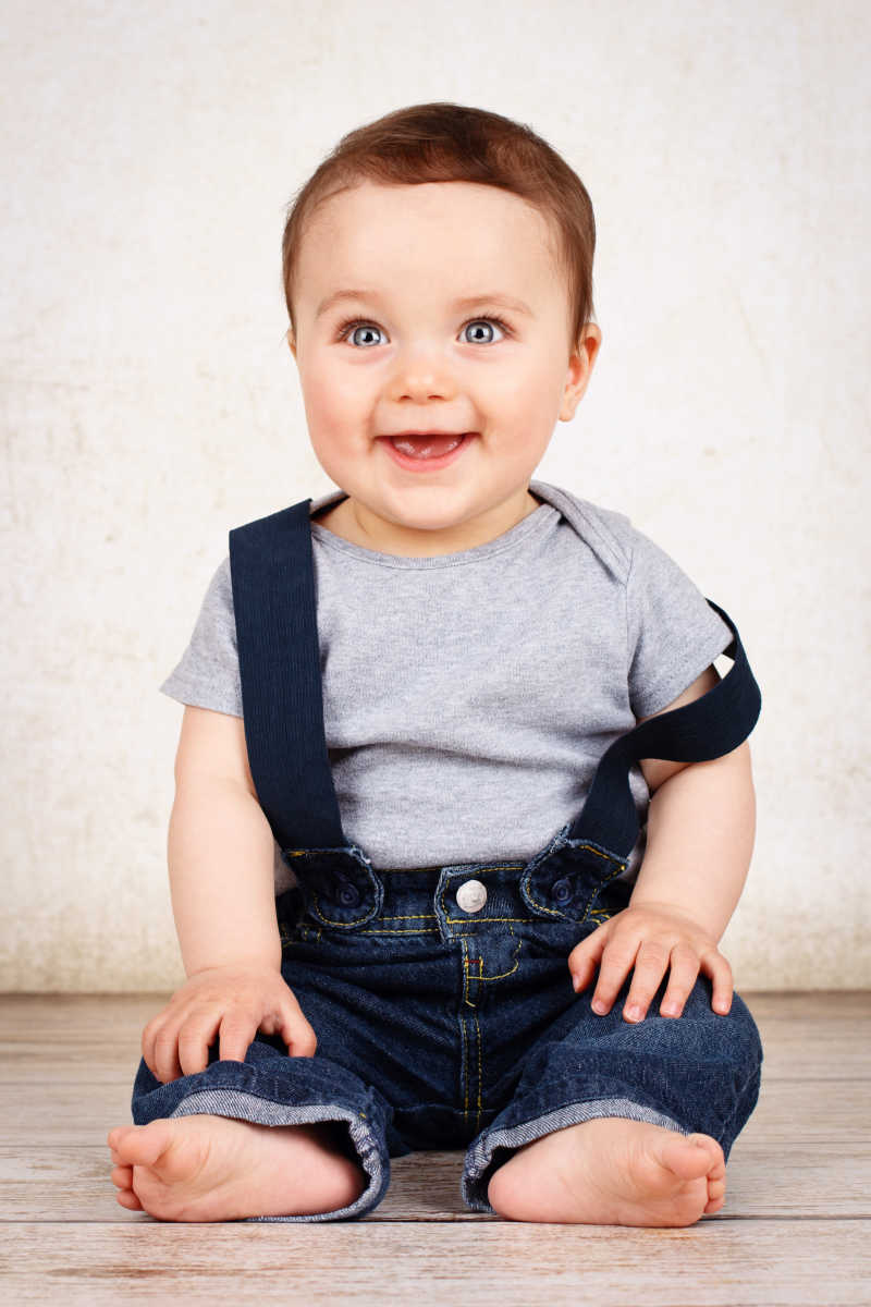 白色背景下坐在地板上微笑的小宝宝