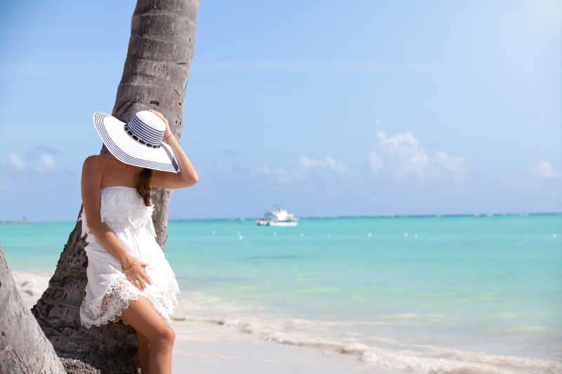 蓝天下蓝色海边白色沙滩上海边穿着白色裙子戴着白色帽子的美女