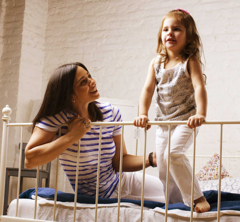 年轻微笑的母亲在家中与女儿玩耍