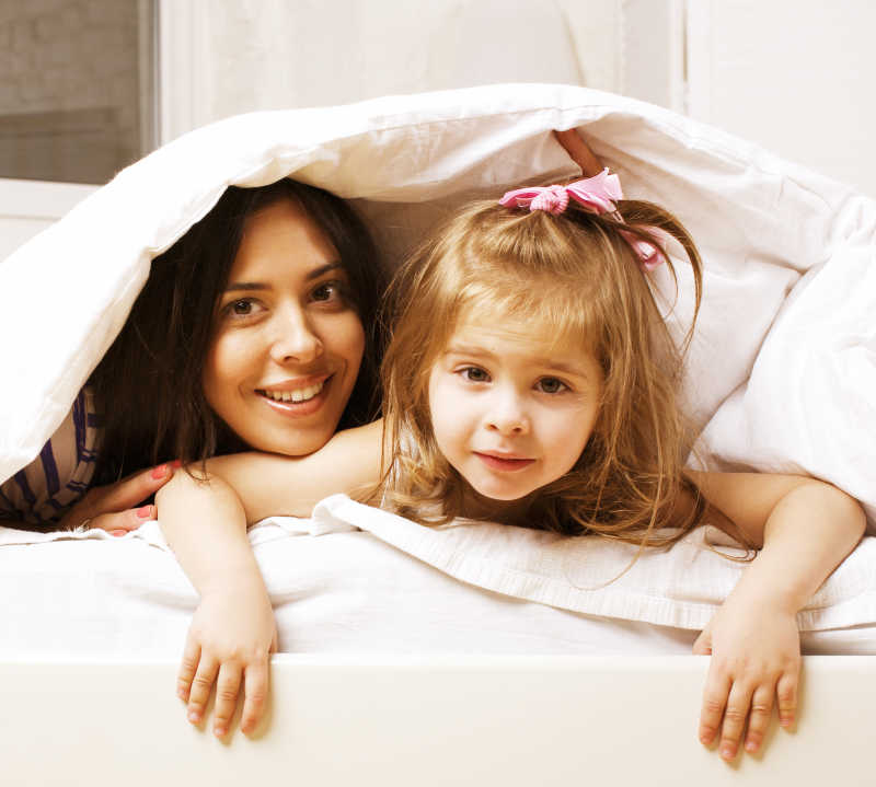 微笑的一对母女躲在被窝里
