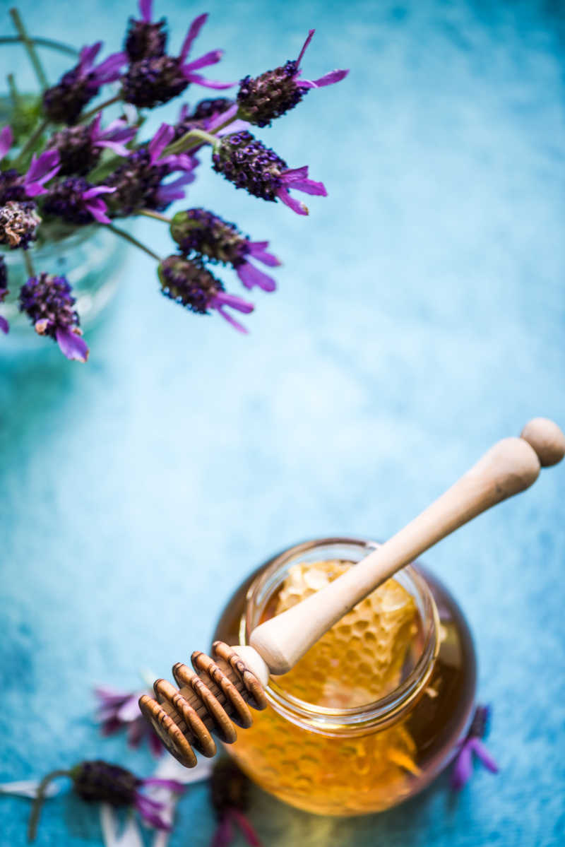 蓝色背景下的蜂蜜罐和薰衣草