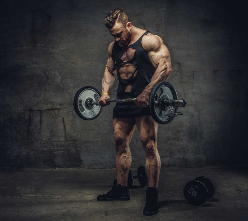肌肉发达的健美运动员站在灰色墙壁前面