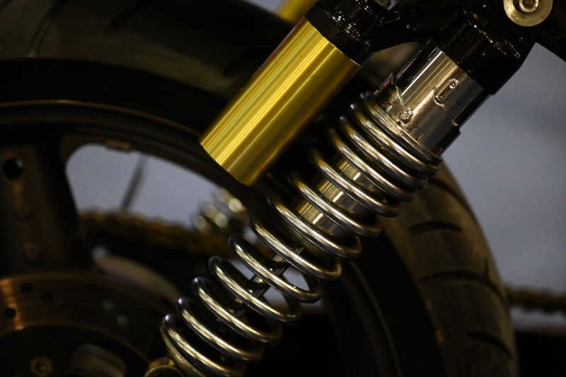 黑色背景下摩托车悬架上的金色弹簧状零件
