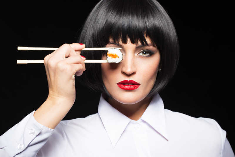 把寿司放在眼部的短发女人