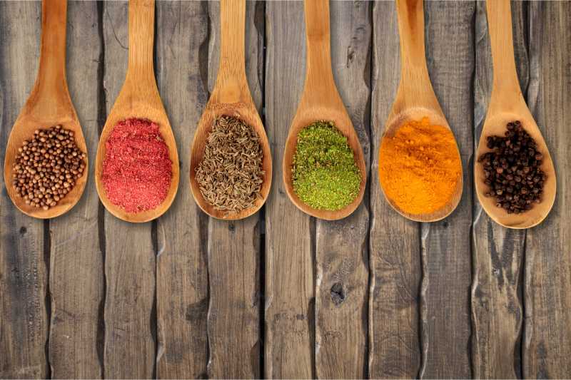 木制背景下勺子里丰富的香料