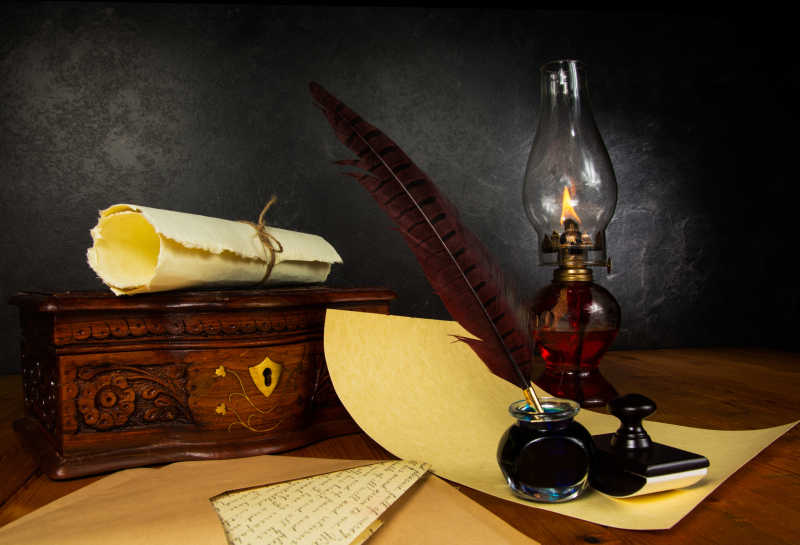 木桌上的羽毛笔煤油灯和卷轴纸张
