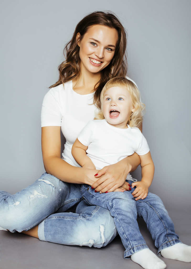 微笑的时尚妈妈带着金发的女儿