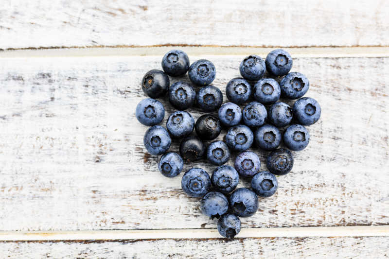 木制板上摆成心形的蓝莓