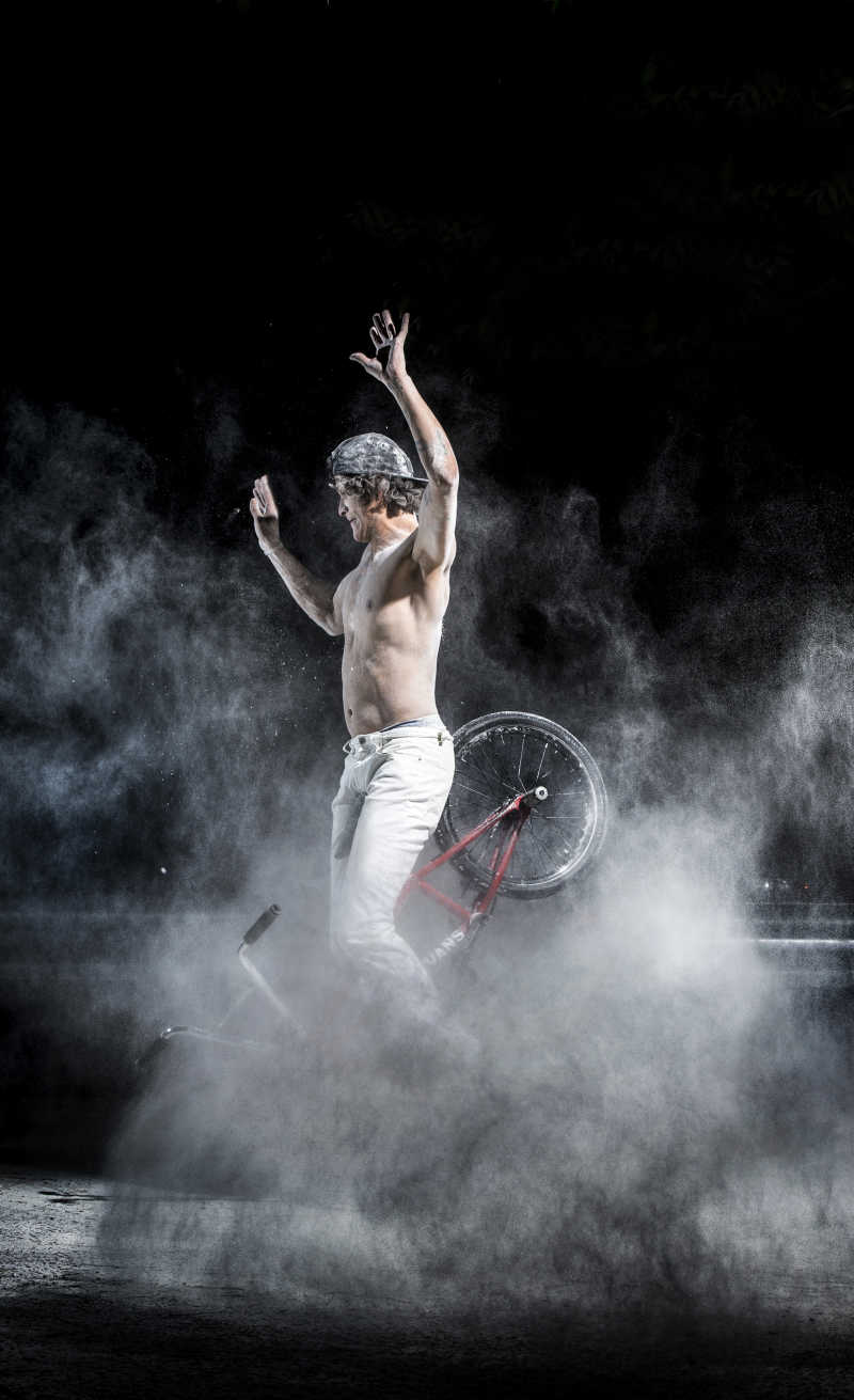 烟雾中做小轮车特技的年轻男子