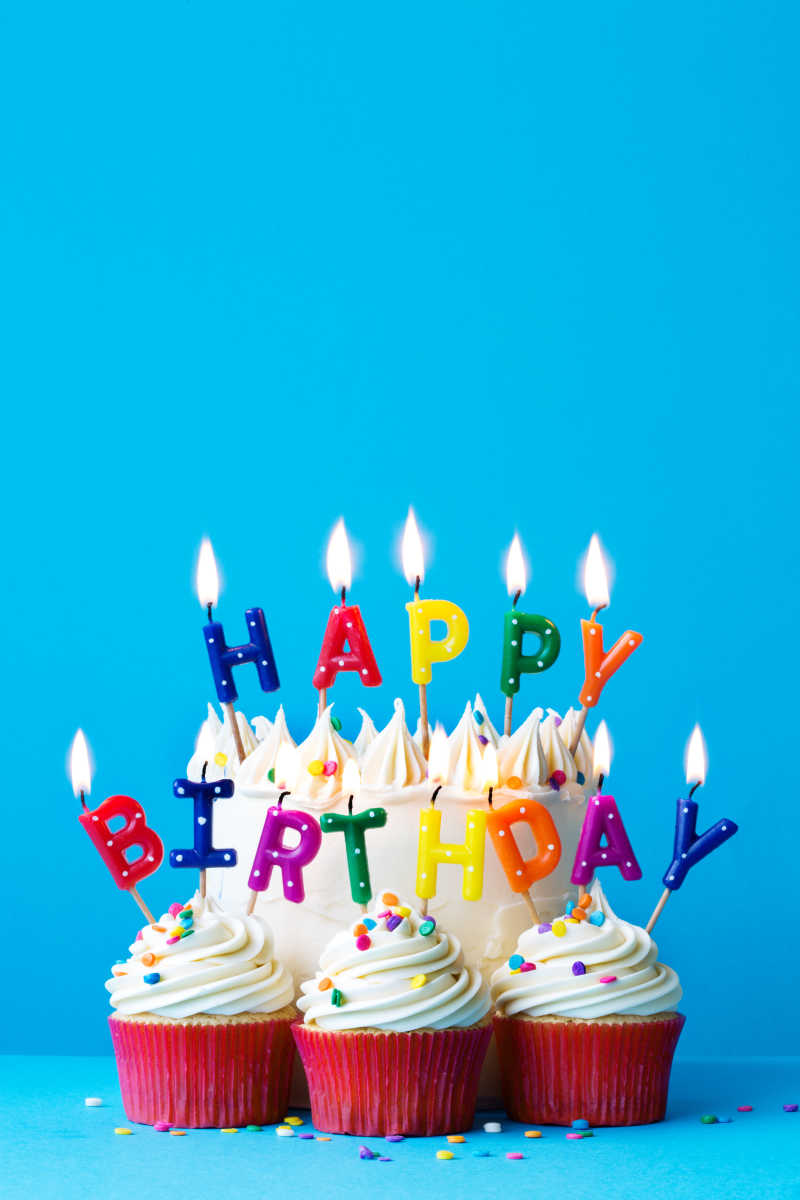 蓝色背景上插着生日快乐蜡烛的蛋糕