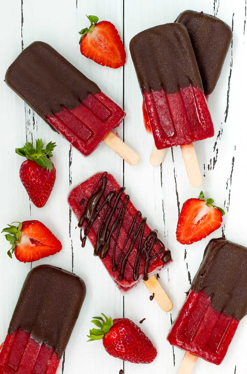桌子上的美味的蘸有巧克力的草莓冰棍