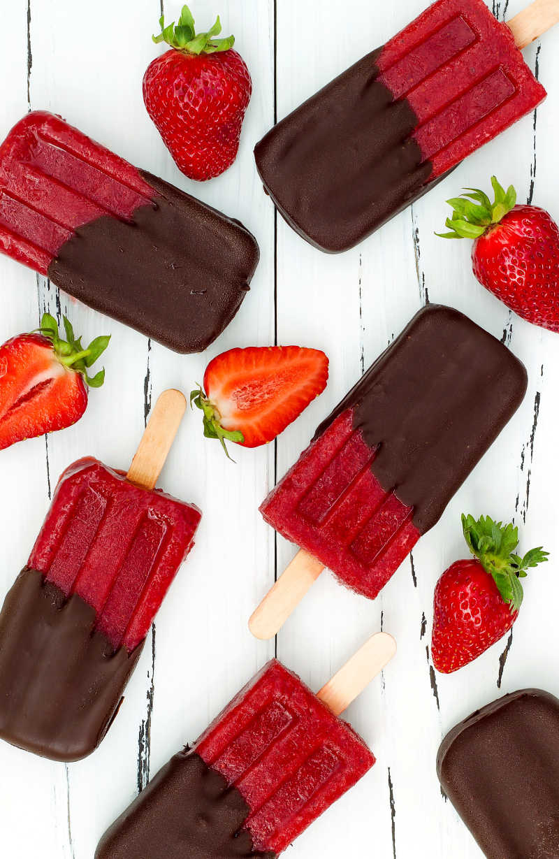 桌子上蘸着巧克力的草莓冰棍