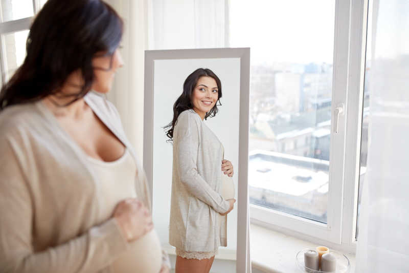 幸福的孕妈妈望着镜子