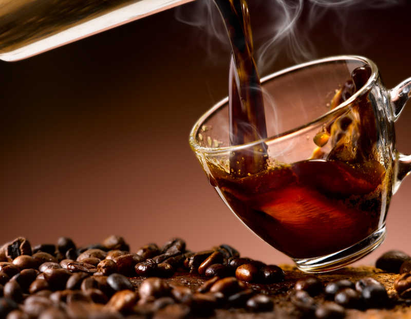 倒入玻璃杯中的刚煮好的咖啡和咖啡豆