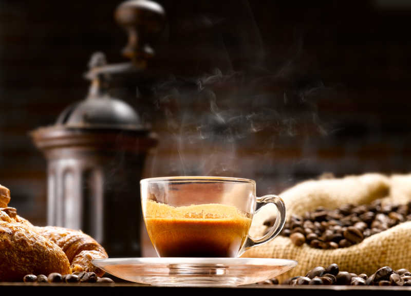 玻璃杯中冒着热气的咖啡和咖啡豆