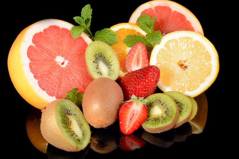 黑色背景下的草莓柚子柠檬猕猴桃和橘子