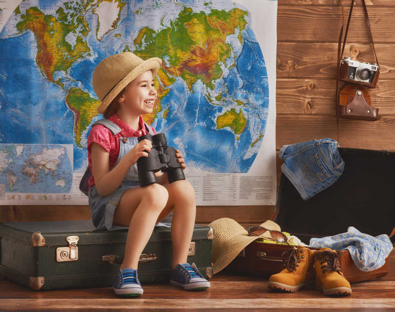 孩子坐在地图前手拿望远镜