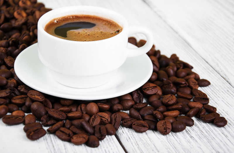 白色背景下的一堆咖啡豆和一杯咖啡