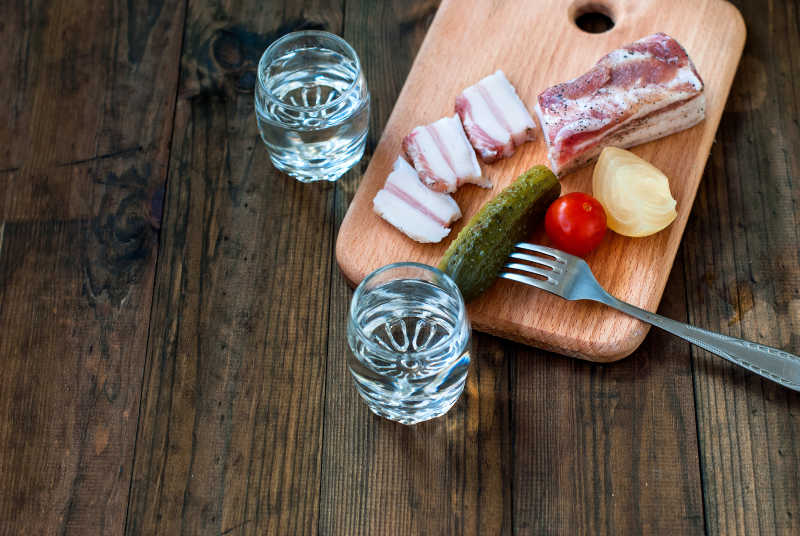 玻璃杯中的伏特加和木桌上的蔬菜肉