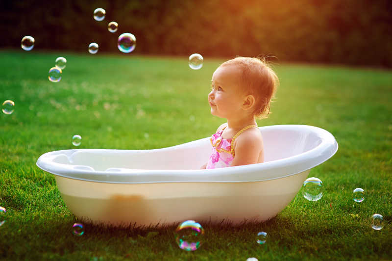 户外草地上洗泡泡浴的小女孩