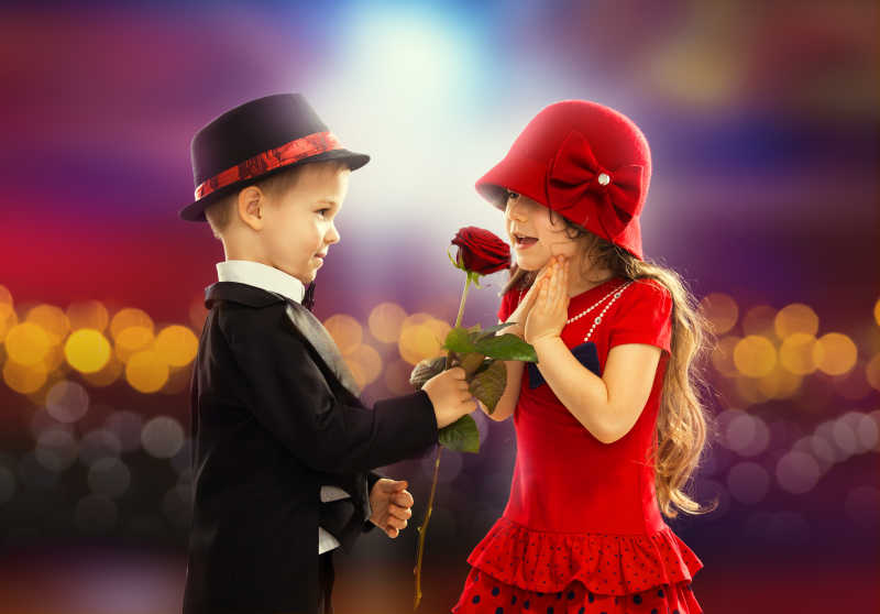 穿着西装带着帽子的男孩拿着玫瑰送给女孩