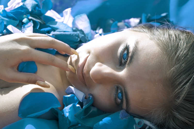 有着蓝色眼睛的白人女人躺在蓝色玫瑰中