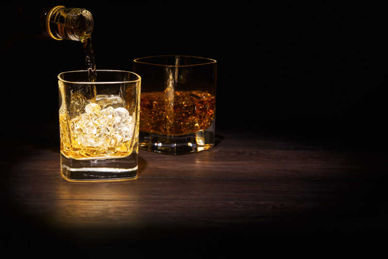 放在木桌上的两杯威士忌酒杯