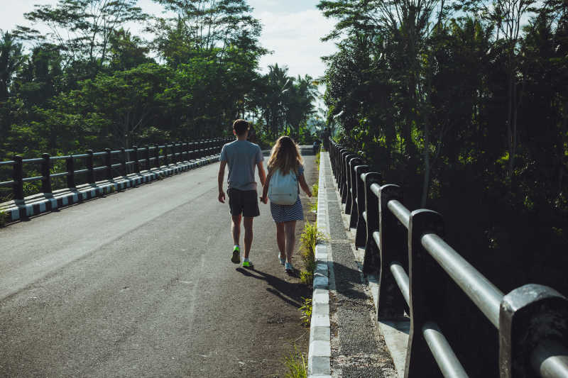 一对浪漫情侣手牵手的背景图片-正在桥上离去的情侣素材-高清图片