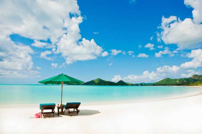蓝天下放着遮阳伞和长椅的美丽海滩
