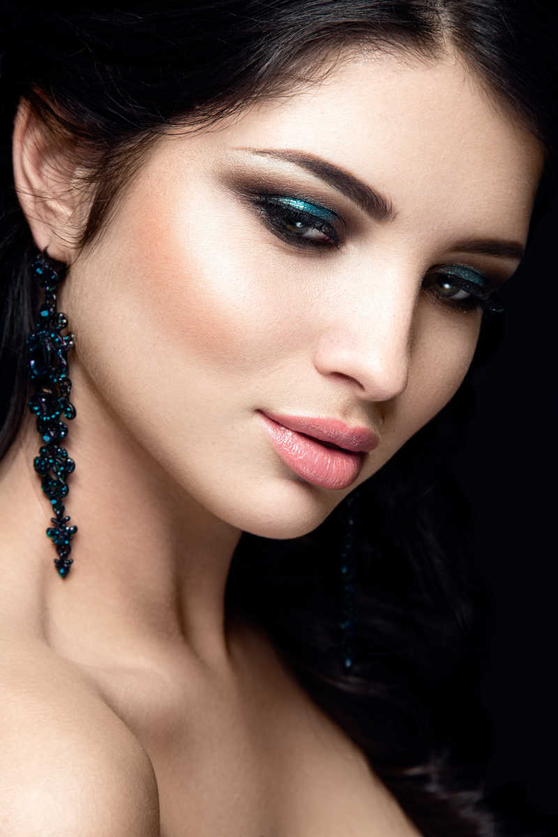 黑色背景下画着孔雀蓝色眼妆的美女