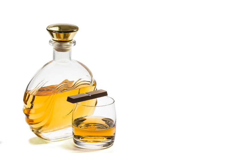 白色背景下的巧克力与瓶和玻璃的威士忌